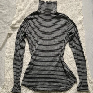 Randig polo!💋 - Slimmad ribbad polotröja i grått med svarta horisontella ränder. Perfekt för lager-på-lager. Stilren men ändå en touch av *vad du vill*. Du kan känna dig som Bella Swan eller Amelie eller kanske dig själv! Det står L i plagget men den är stretchig och skulle funka från XS till XL💋