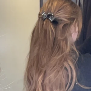 Svart hårklämma med glittrig rosett - Gullig hårklämma som är som en rosett med små svarta diamanter på.