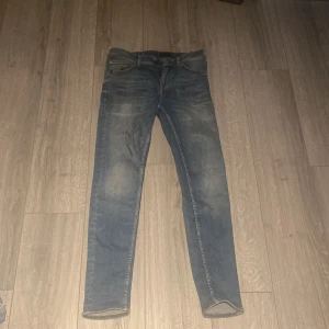 Blå skinny jeans från 7 For All Mankind - Snygga blå jeans från tiger of Sweden med skinny passform och klassisk femficksdesign.  Ett brunt läderpatch med logga bak i midjan. Perfekt för dig som gillar en smal siluett. Storlek:29/32