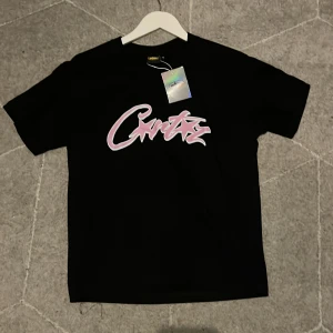 Svart T-shirt från Cortiez med råda tryck - Svart T-shirt från Cortiez med stort råsa graffiti tryck. En skön T-shirt med klassisk rund hals 