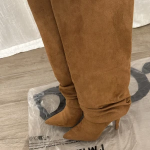 Knähöga stövlar  - Fina knähöga stövlar från Asos i storlek 38, använda 3 gånger med materialet har gått upp lite där bak vid klacken (se bilder) ! Annars så fint skick