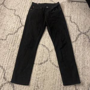 Svarta Levi's 501 jeans straight fit - Svarta Levi's 501 jeans med klassisk straight fit och fem fickor. Byxorna har den ikoniska läderpatchen bak och röd Levi's-tag på fickan. Snyggt minimalistiskt utseende och passar perfekt till sneakers eller boots.
