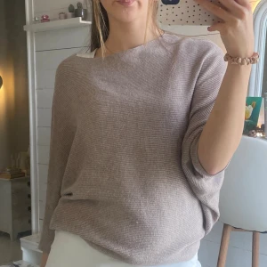Beige ribbad stickad tröja - Säljer en beige stickad tröja med diskret ribbad struktur och avslappnad passform. Tröjan har lång ärm och en lite bredare rund halsringning, perfekt för dig som gillar en chill och enkel stil. Supermjuk och skön att ha på sig.