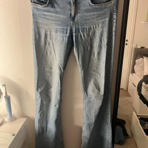 Bootcut jeans från Zara, ljusblå - Säljer ett par ljusblå bootcut jeans från Zara med klassisk femficksdesign och dragkedja. Jeansen har en snygg tvättad look och är tillverkade i bomullsmaterial. Passar dig som gillar retrovibbar och vill ha ett par jeans med lite vidare ben.