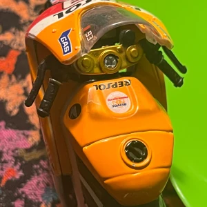 Repsol Honda MotoGP Modellmotorcykel - Detaljerad modell av Repsol Honda MotoGP motorcykel med autentiska dekaler och färger. Orange fälgar, Bridgestone-däck och GAS-sponsring. Skicket är mycket bra, inga synliga skador eller slitage. Perfekt för samlare eller som dekoration.