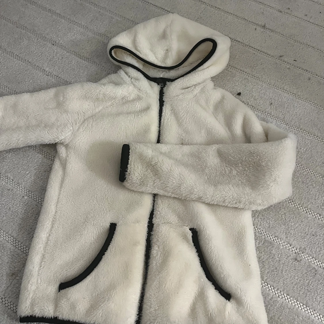 Vit teddyjacka med huva och svarta detaljer