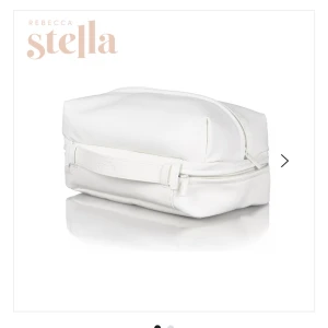 Vit necessär från Rebecca Stella - Snygg och stilren necessär i vitt skinnimitation från Rebecca Stella. Väskan har en rektangulär form, dragkedja upptill och ett vinrött innerfoder som ger en lyxig känsla. Perfekt för att organisera smink eller småprylar när du är på språng.