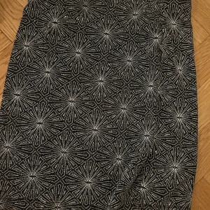 Glittrig svart kjol från H&M Divided - Säljer en svart glittrig kortkjol från H&M Divided i storlek XS. Kjolen har ett unikt geometriskt mönster i silver som verkligen sticker ut. Perfekt för dig som vill ha något extra till outfiten. Resår i midjan för skön passform.