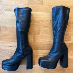 Svarta River Island platform boots strl 38 - Snygga knähöga stövlar med rejäl klack och platå. Endast använda en gång – i nyskick! Tyvärr något för stora för mig, annars hade jag behållit dem.  • Storlek: 38 • Färg: Svart • Material: Imitation leather • Klackhöjd: ca 12 cm • Platå: ca 4 cm • Bekväma att gå i trots höjden  Perfekta till vinterns outfits – både till klänning och jeans.  Nypris: 1069:-