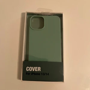 Cover för iPhone 13/14 - Ny, stilren grön mobilskal för iPhone 13 och iPhone 14. Levereras i originalförpackning, utan synligt slitage eller defekter. Ger effektivt skydd mot repor och stötar samtidigt som den behåller en tunn och elegant design.