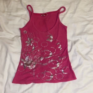 Rosa ribbad linnetopp med silvertryck - Säljer en rosa ribbad linnetopp med  ett coolt silvertryck med blommor på framsidan. Toppen är figurnära och har ett stretchigt mateial, funkar som både XS och S!🥰❣️
