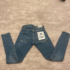 Blå skinny jeans från Karve W26 - Snygga blå jeans från Karve i modellen skinny med droppad gren. Jeansen har klassisk femficksdesign, stentvättad finish och är tillverkade av 95% bomull, 3% polyester och 2% elastan. Passar dig som gillar en smal siluett och modern look. Storlek W26