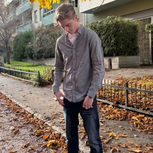 Grå skjorta från Premium By Jack&Jones  - Snygg grå skjorta från Premium By Jack&Jones  med snygg krage och svarta knappar. Skjortan har lång ärm och rak passform, tillverkad i mjuk bomull. Modellen är 181cm!