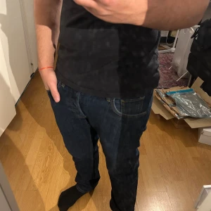  Lee Daren Button jeans W30 L30 - Snygga mörkblå jeans från Lee, modell Daren Button Fly. Klassisk femficksdesign med gylf med knappar och kontrastsömmar. Jeansen har rak passform och är tillverkade i slitstarkt denimtyg. Perfekta för dig som gillar en tidlös look. Dom sitter även bra med häng!