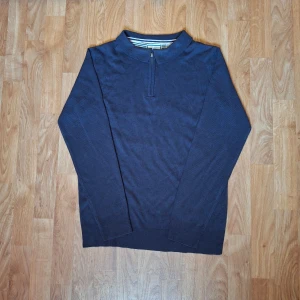 Marinblå stickad tröja Brave Soul - Snygg marinblå stickad tröja från Brave Soul med half zip och ståkrage. Tröjan har långärmad design och ribbade muddar vid ärmslut och nederkant. Insidan av kragen har ett randigt mönster i vitt och blått som ger en cool detalj. OBS helt ny men ingen prislapp kvar!