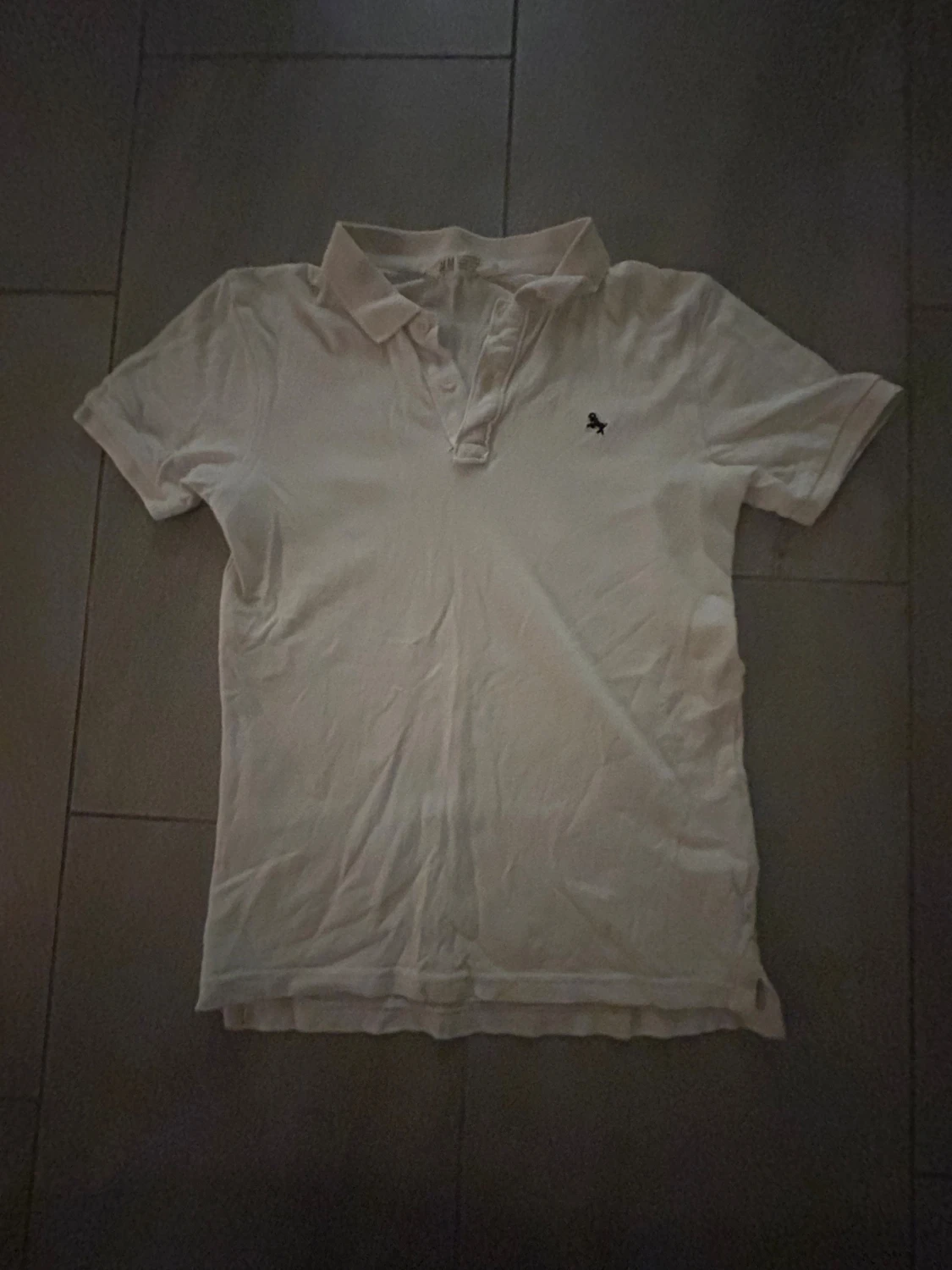 Vit piké med liten broderad logga. Pojke