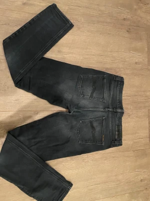 Mörkblåa jeans från Nudie Jeans, 29/32 - Säljer ett par mörkblåa jeans från Nudie Jeans då dom inte passar mig längre. Dom är riktigt sköna och inte mycket använda. Skicket är väldigt bra och mitt pris är 450 kr. Kom med prisförslag!