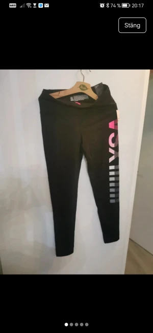 Svarta VSX Sport leggings med tryck träningsbyxor  - Snygga svarta leggings från VSX Sport med coolt rosa och vitt tryck längs benet. De har medium midja, tight passform och är gjorda i stretchigt nylonmaterial som andas. Perfekta för träning och har dold ficka i midjan.ett par Victoria’s Secret Sport “Knockout Tight” — en  träningstights i kollektionen VSX Sport. detaljerna: Modell: Knockout Tight Passform: Medium Rise, Form-Fitting Märke: Victoria’s Secret Sport (VSX) Funktioner: “Smooth waistband” som sitter på plats “Hidden waistband pocket” “