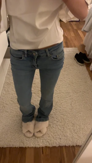 Blå bootcut jeans med låg midja - Säljer ett par ljusblå jeans med bootcut passform och låg midja. Klassisk femficksmodell med knapp och dragkedja framtill. Jeansen har en snygg tvätt och är tillverkade i jeansmaterial med lite stretch för skön passform.