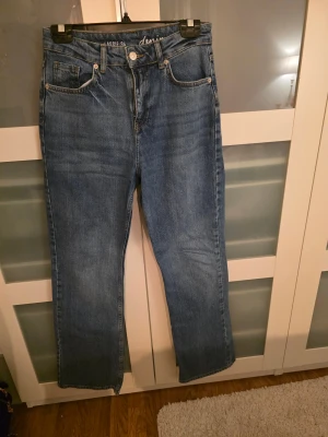 Blå denimjeans Lassie 34 straight fit - Snygga blå jeans från Lassie i klassisk straight fit med fem fickor och knappgylf. Jeansen har en normal midja och är tillverkade i slitstarkt denimtyg. Perfekt för dig som gillar en enkel och tidlös look.
