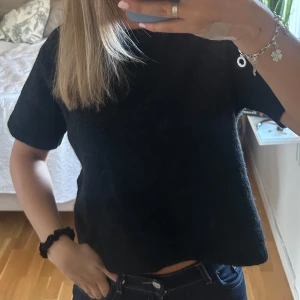 Svart stickad tröja Gina Tricot S - Kortärmad svart stickad tröja från Gina Tricot i storlek S. Tröjan har en rund halsringning med ribbade detaljer och är gjord i ett mjukt, lite luddigt material. Perfekt att styla med jeans eller kjol för en chill look.