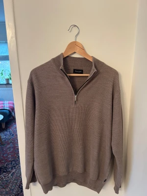 Beige stickad half zip-tröja Sand - Säljer en beige stickad tröja från Sand Copenhagen med half zip-dragkedja och hög krage. Tröjan har lång ärm och en snygg, diskret struktur i materialet. Perfekt för lager-på-lager. Storlek M