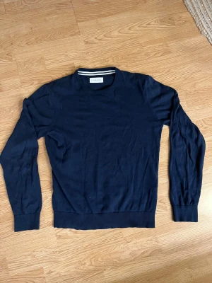  Pier One tröja - Snygg mörkblå stickad tröja från Pier One med rund hals och ribbade muddar vid ärmslut och nederkant. Enkel och stilren design som funkar till många olika looks. Perfekt för dig som gillar klassiska plagg med en modern touch.