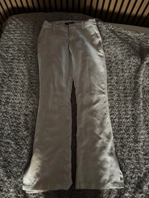 Bikbok Vita bootcut kostymbyxor med fickor - Snygga vita byxor med bootcut-modell och klassiska fickor fram. Byxorna har hällor för bälte och är tillverkade i ett mjukt bomullsmaterial. Perfekta för dig som gillar en stilren och fräsch look.
