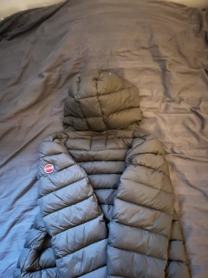 Colmar gråblå dunjacka med huva - Säljer en dunjacka från Colmar i grönt/grått med blått foder och huva. Jackan har två fickor med dragkedja och ett snyggt Colmar-märke på ärmen. Puffad design och hel dragkedja framtill. Perfekt för kalla dagar när du vill vara både varm och stilren. Storlek M. Säljer då den är lite för kort för mig. Den har 2 små fläckar på ryggen som inte syns med blotta ögat. Priset inte hugget i sten