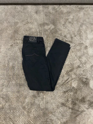 Svarta Jacob Cohen 622 Comfort jeans - Svarta jeans från Jacob Cohen, modell 622 Comfort. Snygga röda sömmar och broderade detaljer på insidan. Klassisk femficksdesign, smal passform och dragkedja framtill. Materialet är mjukt och stretchigt för extra komfort.