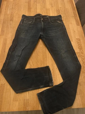 Replay Anbass slim fit jeans, mörkblå - Snygga Replay Anbass jeans i mörkblå tvätt med slim fit-passform. Klassisk femficksmodell, diskreta slitningar och detaljerade sömmar. Jeansen är tillverkade i stretchigt denim för extra komfort och har en stilren look som funkar till sneakers eller boots.
