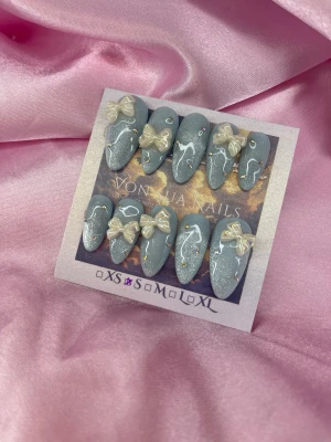 Mochi Ice (S);Medium Almond - Säljer ett set med press-on naglar i glittriga cateye blått med små kristaller. Naglarna är medium mandelformade och dekorerade med pärlemorskimrande 3D-rosetter. Perfekt för dig som vill ha en söt och unik look.S: 15 mm, 11,5 mm, 12 mm, 11 mm, 9 mm  