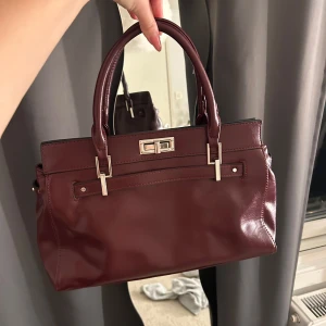 Vinröd handväska  - Vinröd handväska från bershka med silver detaljer. Bra skick.
