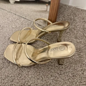 Guldiga sandaler med klack från Boohoo - Säljer ett par jättefina klackar från Boohoo. De är endast använda en gång. 