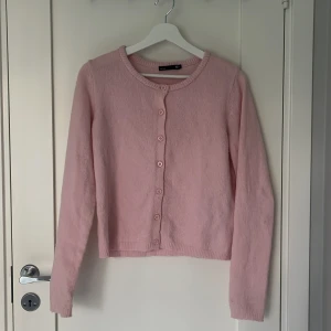 Rosa kofta från 157, XS - Söt ljusrosa kofta från 157 i storlek XS. Koftan har rund hals, långa ärmar och knappar framtill. Stickad i mjukt material som känns skönt mot huden. 