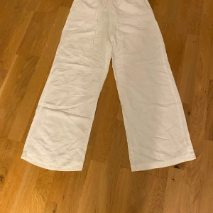 Vita linnebyxor från H&M, wide fit XS - Snygga vita linnebyxor från H&M i storlek XS. Byxorna har en relaxed wide fit och är tillverkade i en skön linnemix som passar perfekt för varmare dagar. De har raka, vida ben och en enkel, clean look.
