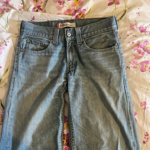 Levi's 509 low-waist - Ljusblå Levi's 509 jeans med klassisk femficksdesign och raka ben. Jeansen har låg midja och är tillverkade i mjukt denimtyg. Snygga kontrastsömmar och ikonisk läderpatch baktill. Perfekta för en avslappnad och stilren look.