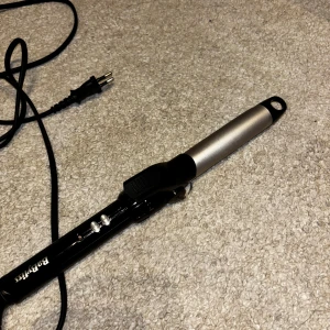 BaByliss Locktång - BaByliss locktång med silverfärgad värmecylinder och svart handtag. Utrustad med strömbrytare och indikatorlampa. Sladden och kontakten är i gott skick. Inga synliga defekter eller större slitage, fungerar utmärkt för att skapa lockar.