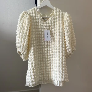 Krämvit blus med puffärm från Wera - Krämvit  blus från Wera med puffiga trekvartsärmar 