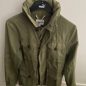 Olivgrön field jacket från Pier One - Säljer en fet field jacket i olivgrön från pier one i storlek S, modellen är ca 180cm. Hör av dig vid funderingar!