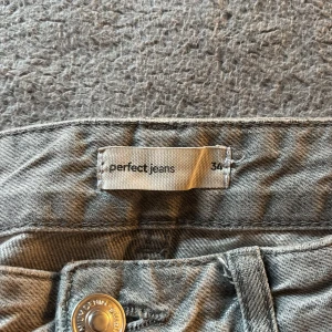 Gråa wide jeans från Gina Tricot - Gråa jeans från Gina Tricot i modellen Perfect Jeans. De har en rak och wide passform med hög midja och slitna, fransiga benslut och "slitna" detaljer. Jeansen är tillverkade i denim och har klassiska fem fickor samt knapp- och dragkedjestängning. Säljer pga använder inte längre. Pris kan diskuteras. skriv för fler bilder. 