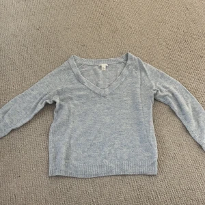 Ljusgrå v-ringad tröja H&M XS - Ljusgrå v-ringad tröja från H&M Basic i storlek XS. Tröjan har långa ärmar, ribbade muddar och nederkant. Perfekt för lager-på-lager och enkel att matcha med jeans eller kjol.