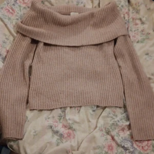 Ljusrosa ribbad offshouldertröja H&M - Superfin ribbstickad ljusrosa tröja från H&M med bred offshoulderkrage. Långärmad och i mjukt material, perfekt för kyliga dagar. Snygg att styla med jeans eller kjol för en trendig look.