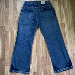 Blå jeans från Southpole Relax Fit - Säljer ett par blå jeans från Southpole i Relax Fit-modell. Jeansen har raka ben, klassiska fem fickor och tydliga slitningar vid benslut och framtill. Tillverkade i bomull för en skön och avslappnad känsla. Perfekta för dig som gillar en loose och avslappnad stil.