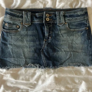 Blå jeanskjol - Blå vintage liknande jeanskjol med detaljer på bakfickorna. Lite osäker på storlek men skulle gissa på en S.