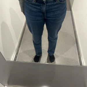 Blå jeansbyxor från Denim 1953, stl 38 - Säljer ett par klassiska blå jeansbyxor från Denim 1953 i storlek 38. Byxorna har hög midja, raka ben och femficksmodell. Jeansen är tillverkade i robust denim med snygga kontrastsömmar och en tidlös look.