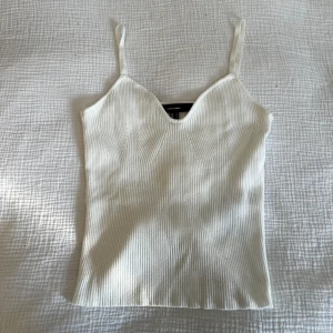 Vit linnetopp från Vero Moda - Säljer en superfin ribbad linnetopp från  Vero Moda i strl S med smala axelband och v-ringad hals. Toppen är figurnära & har en stretchig känsla, använt fåtal gånger. Nypris: 299kr💘 Skickar ditt köp inom 24h!💘