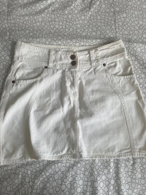 Vit kortkjol från Zoul, storlek 38 - Snygg vit kortkjol från Zoul med dubbla knappar framtill och klassiska jeansfickor både fram och bak. Kjolen har bälteshällor och är gjord i ett stadigt bomullstyg som ger en clean och fräsch look. Perfekt till sommaren och enkel att matcha med allt.ta gärna emot bud och frågor💕😊