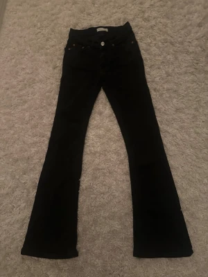 Svarta bootcut jeans från Ginatricot storlek 32 - Säljer ett par svarta bootcut jeans från Ginatricot i storlek 32. Utsvängda ben och silvriga knappar. Super fina!❤️