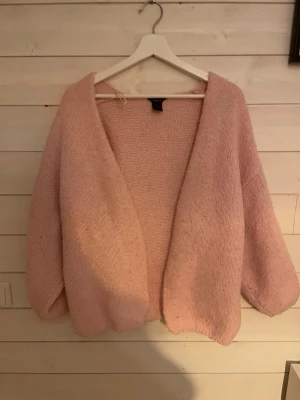 Ljusrosa stickad kofta från Lindex - Mysig ljusrosa stickad kofta från Lindex i storlek XL/2XL. Koftan har en loose passform, är öppen framtill och har långa ärmar. Perfekt för lager på lager under kyliga dagar. Skulle säga att den är mindre i storleken L passar bättre ! Lite nopprig 